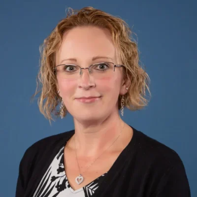 AH-1 A woman with red hair and glasses is wearing black.
